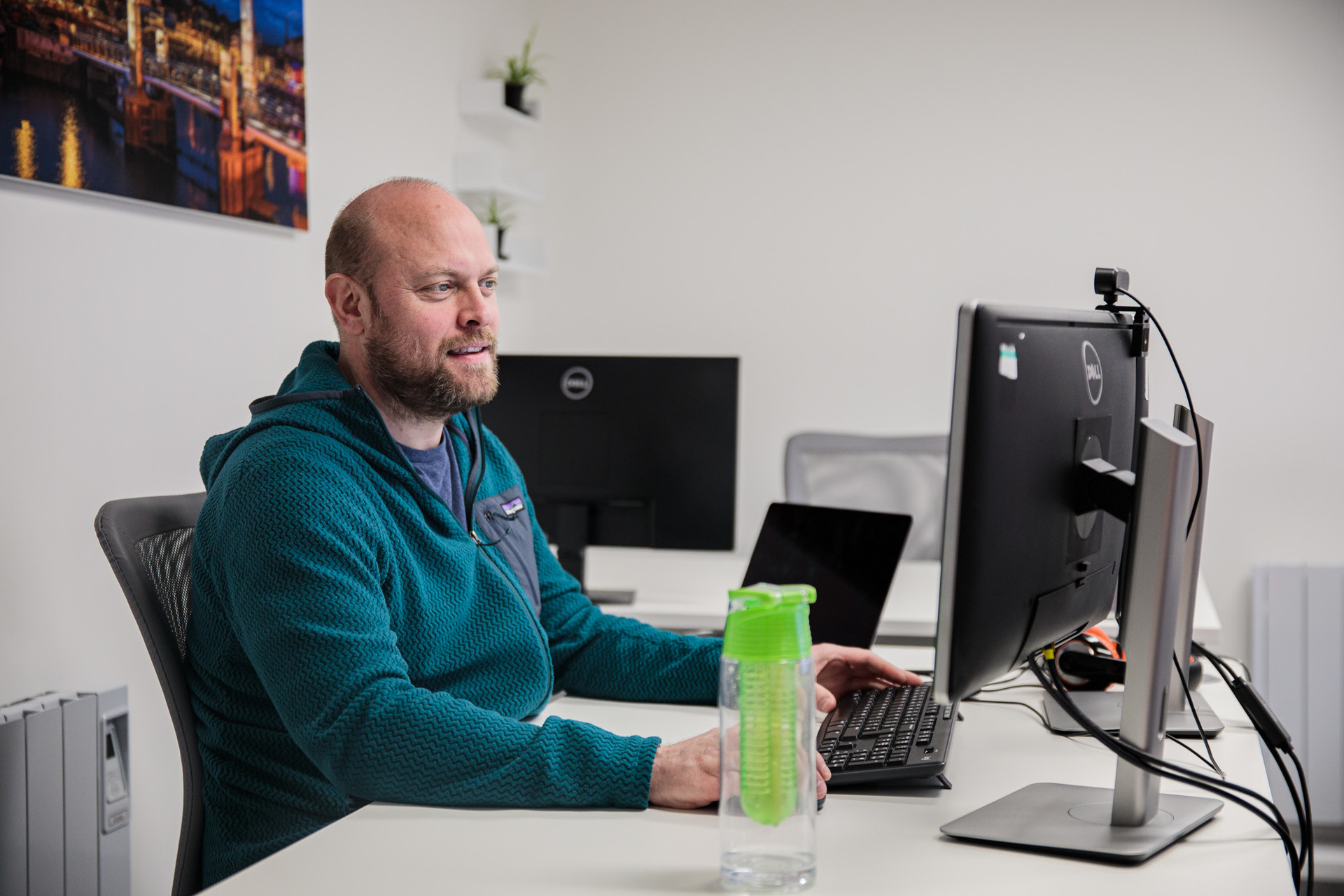 A man sat at his desk looking at a desktop computer
